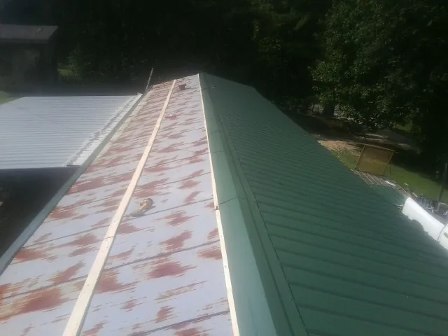Old rusted panels beside newly installed green metal roofing — Wind Damage Roof Repair by Roofing Brothers in South Bloomingville
