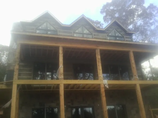 Dormers and porch framing on a large log home under construction — Roof Coating work by our crew in South Bloomingville