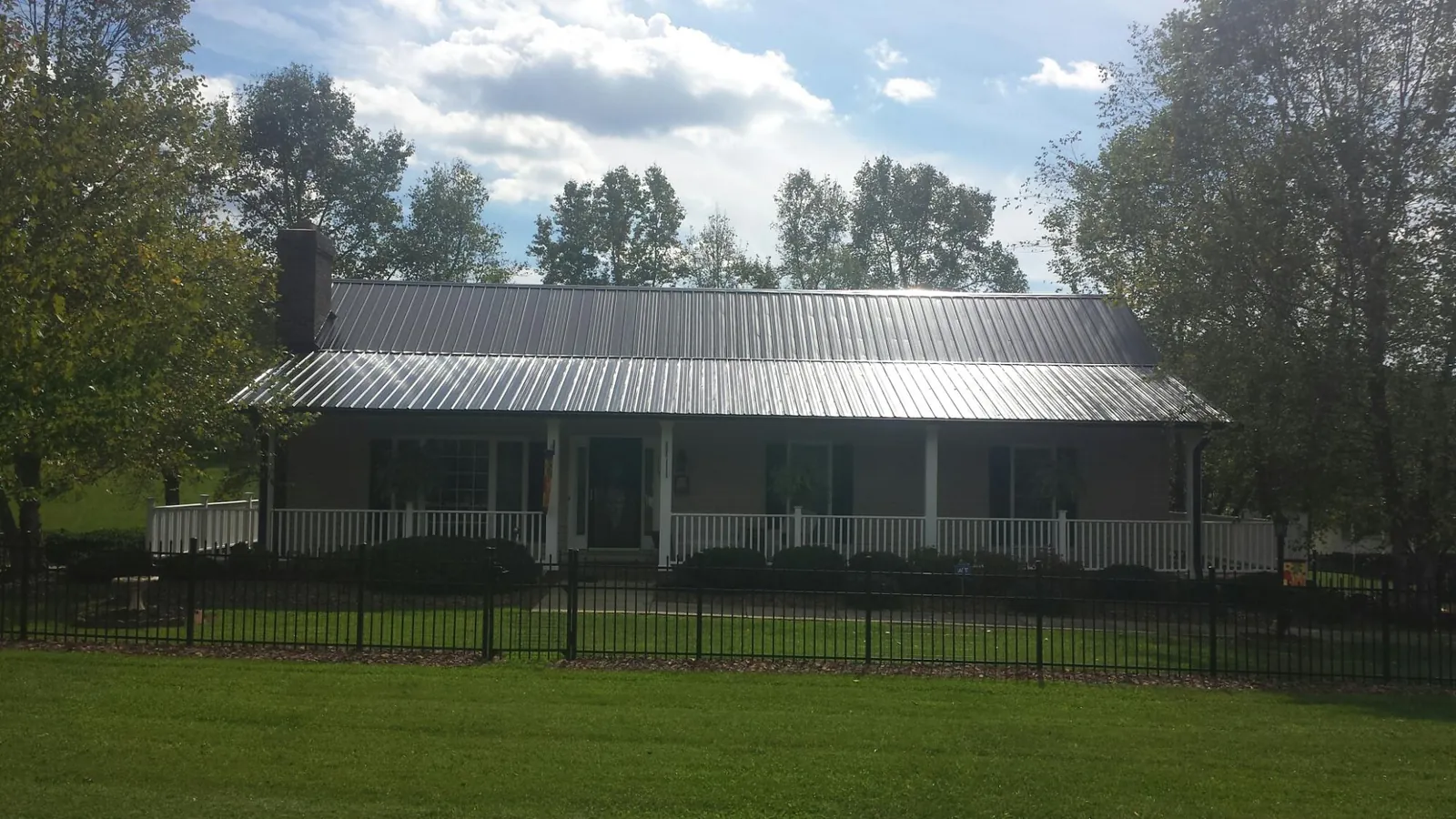 Gray metal roof on a brick ranch with a full width front porch — Gutter Guard Installation work by our crew in South Bloomingville