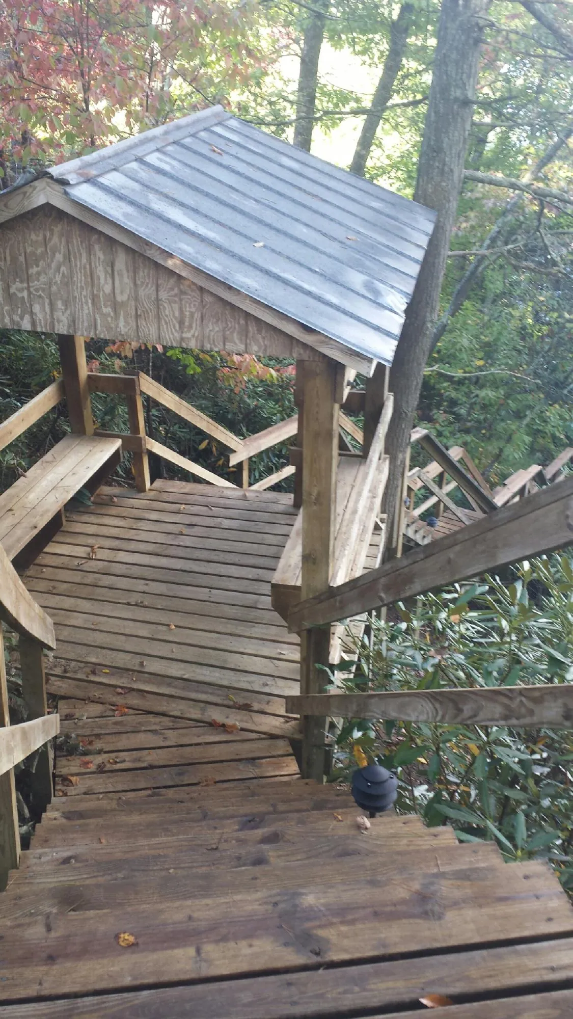 Metal roofed shelter over wooden steps on a wooded walkway — Skylight Repair & Installation work by our crew in South Bloomingville
