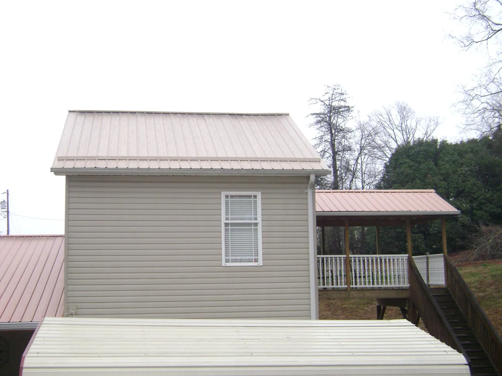 Tan metal roofs on a two story addition and attached porch, from a Roof Replacement job in South Bloomingville