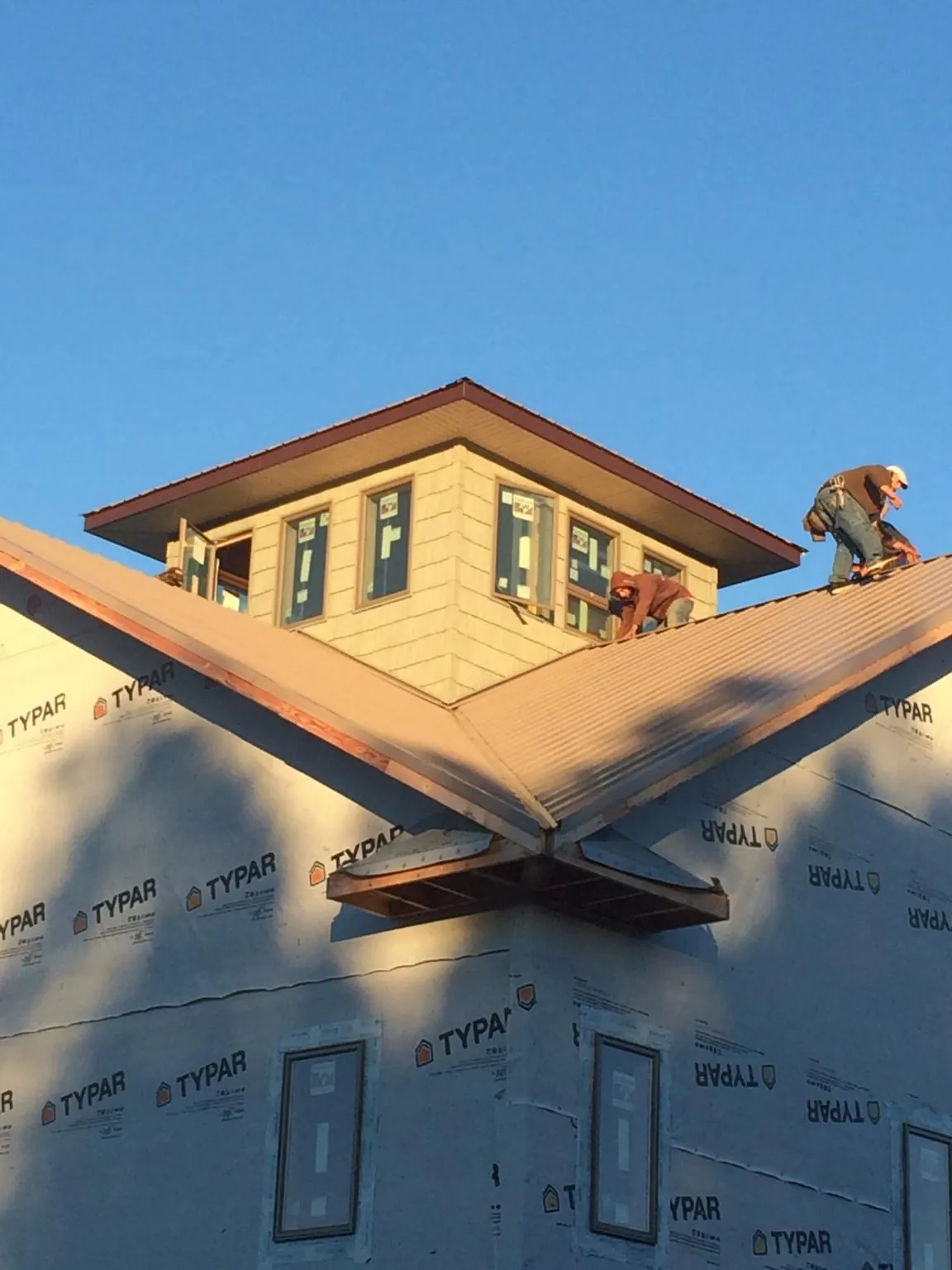 Roofers working around a rooftop cupola on a new metal roof at sunset — Roof Waterproofing in South Bloomingville by Roofing Brothers